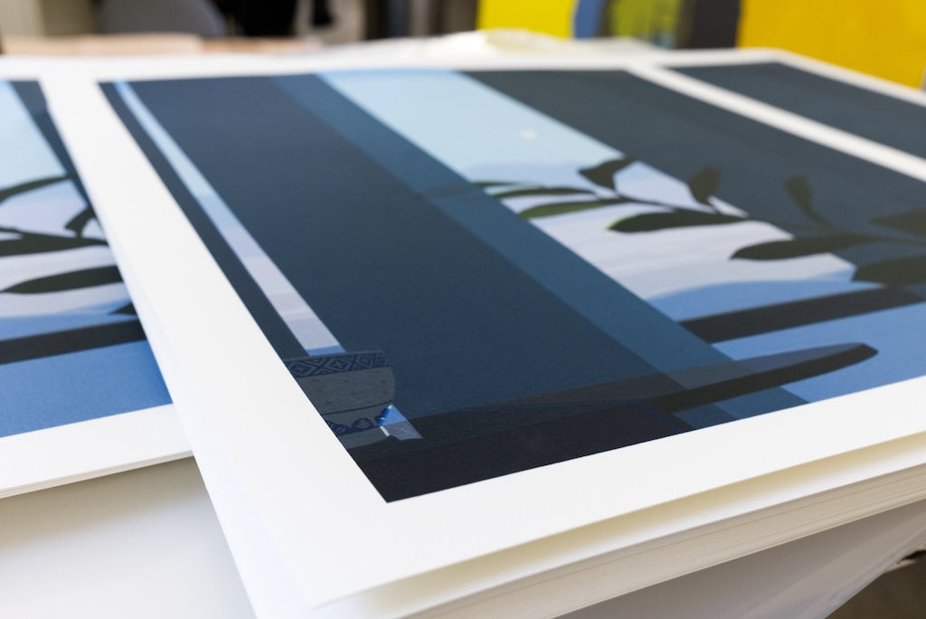 Stack of art prints with a blue and black abstract design on a white surface.