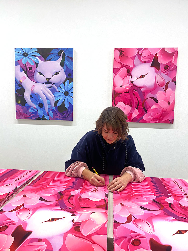 image of artist Megan Ellen MacDonald signing multiple "Bad Kitty" prints