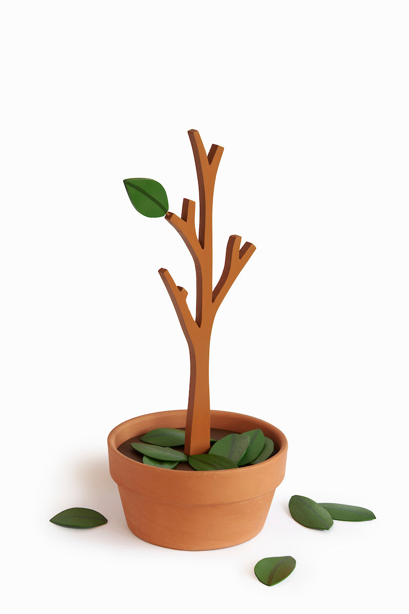 Wooden sculpture of a plant with its leafs falling into the terracotta pot