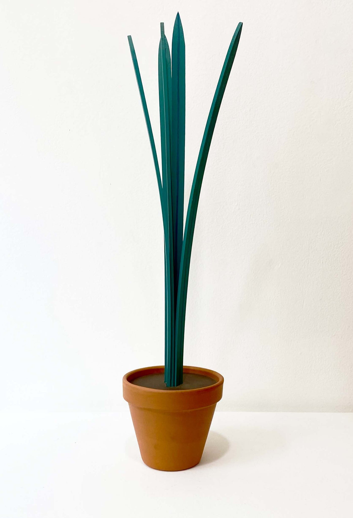Wooden sculpture of tall plant with four leafs in a terracotta pot 