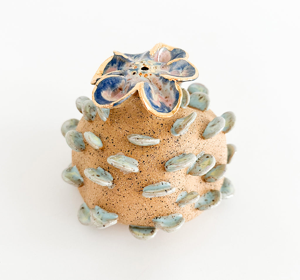 Photograph of a ceramic floral sculpture with multicolor glaze and gilded finish by Jen Dwyer