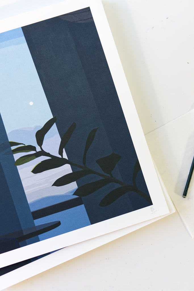Framed artwork with a blue abstract design and leaf silhouette on a white surface