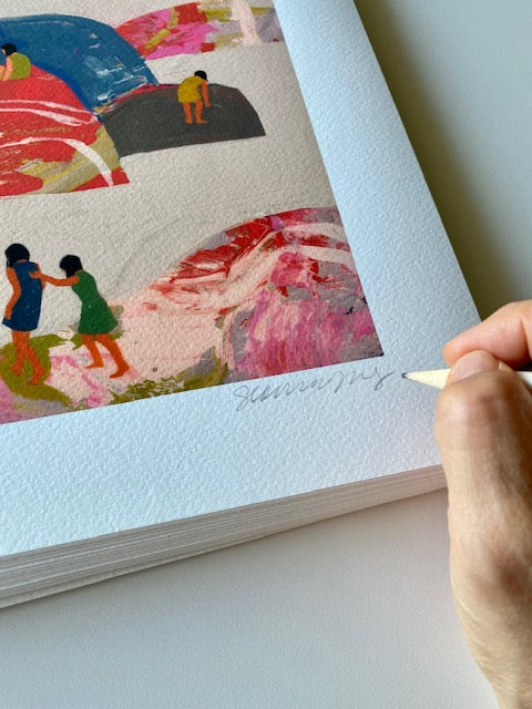 Hand holding pencil signing "Seonna Hong" on print of people standing and climbing onto rainbow colored rocks over a beige background 