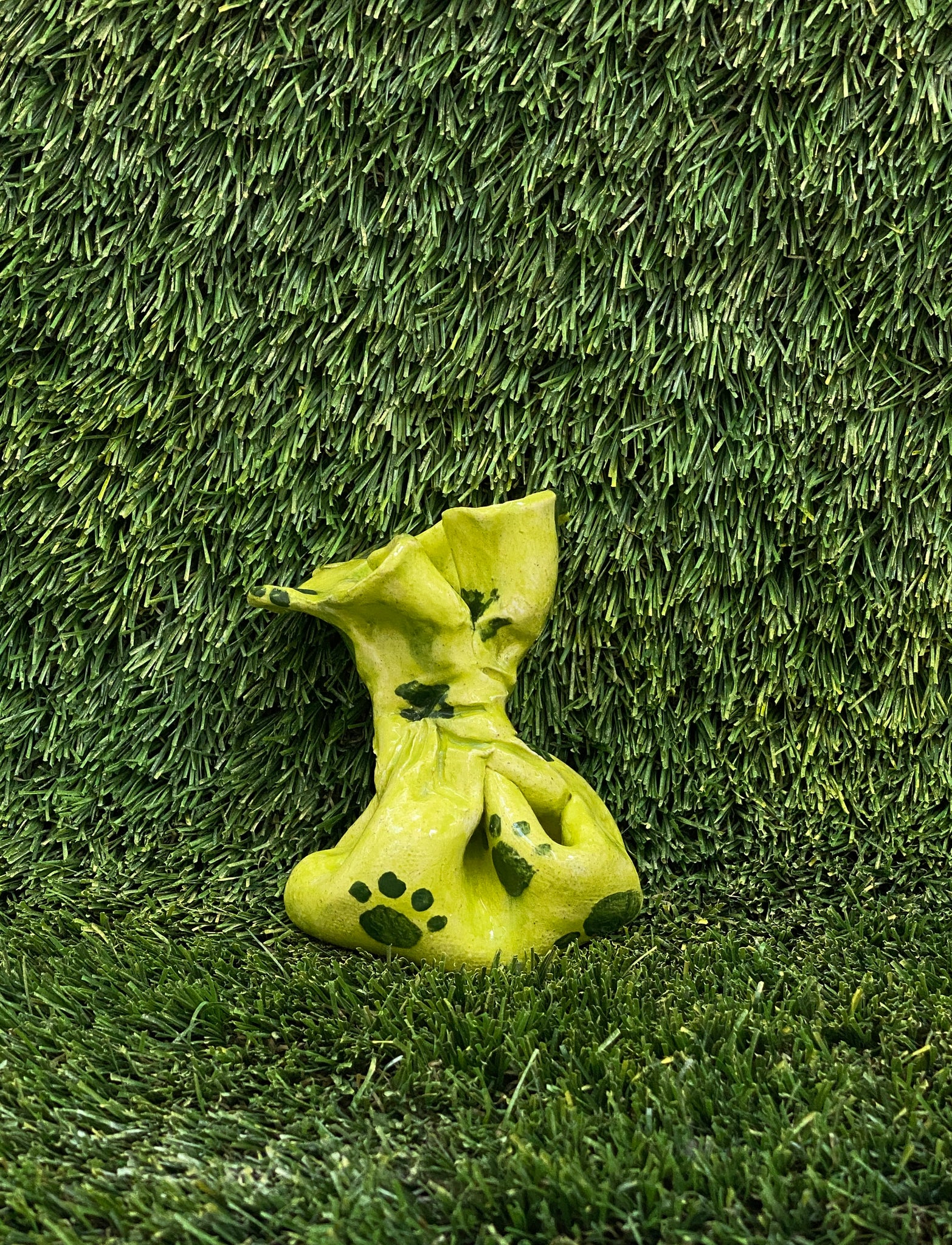 Ceramic sculpture of dog poop bag in green with paw print