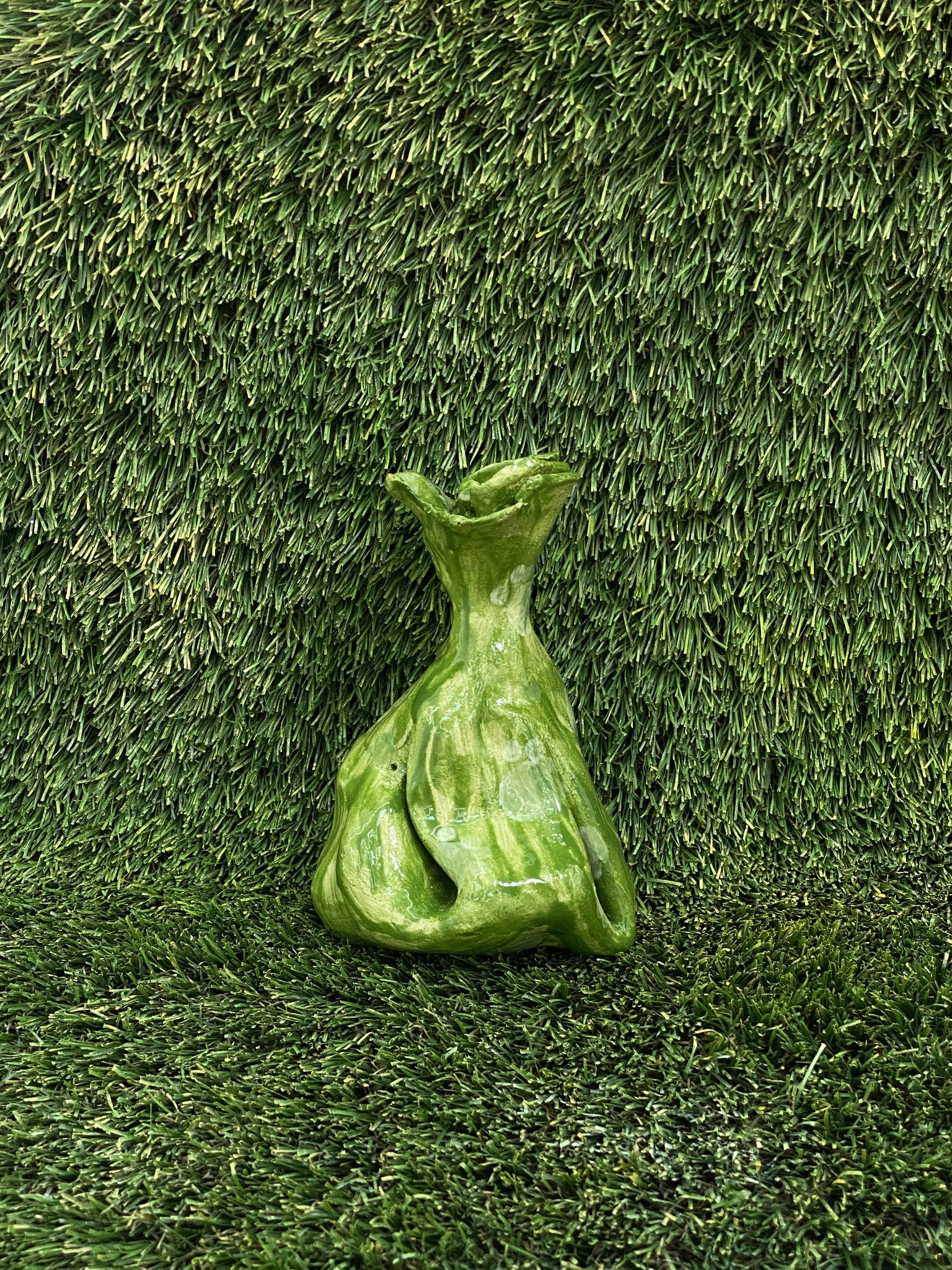 Ceramic sculpture of dog poop bag in olive green