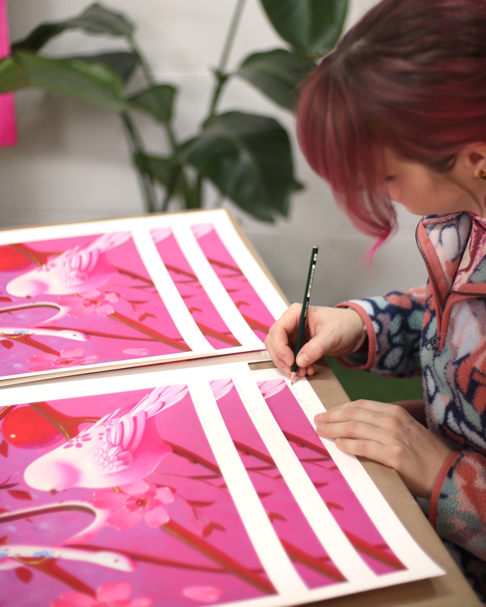 Megan Ellen MacDonald (woman with pink hair) signing prints of fruits on branches with porcelain birds and snake